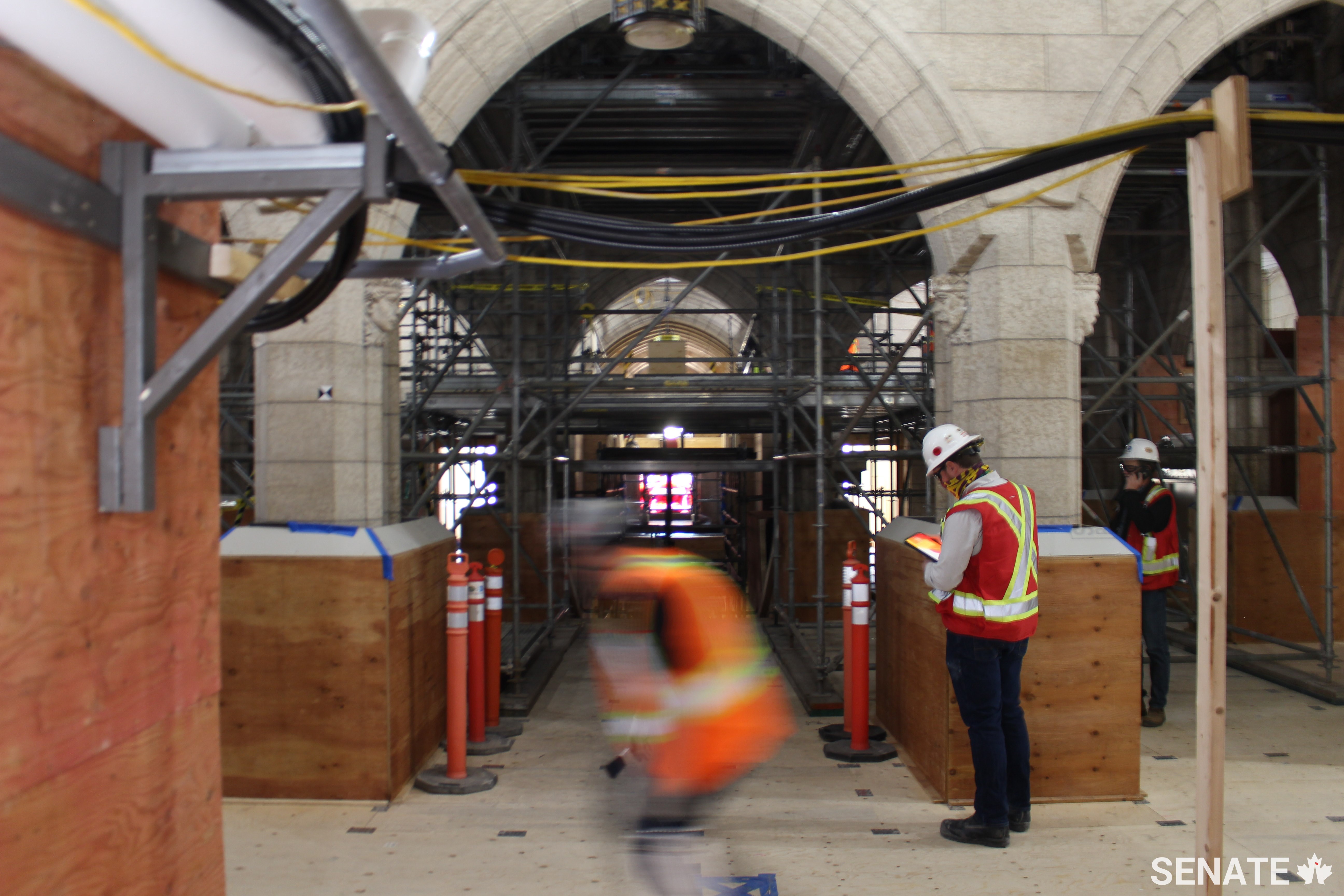 The Senate foyer looks a bit different than it used to. Plywood cladding has been used to protect Centre Block’s historic features during rehabilitation work, and scaffolding is everywhere. The Diamond Jubilee Window is just visible as a soft glow in the centre of the frame.
