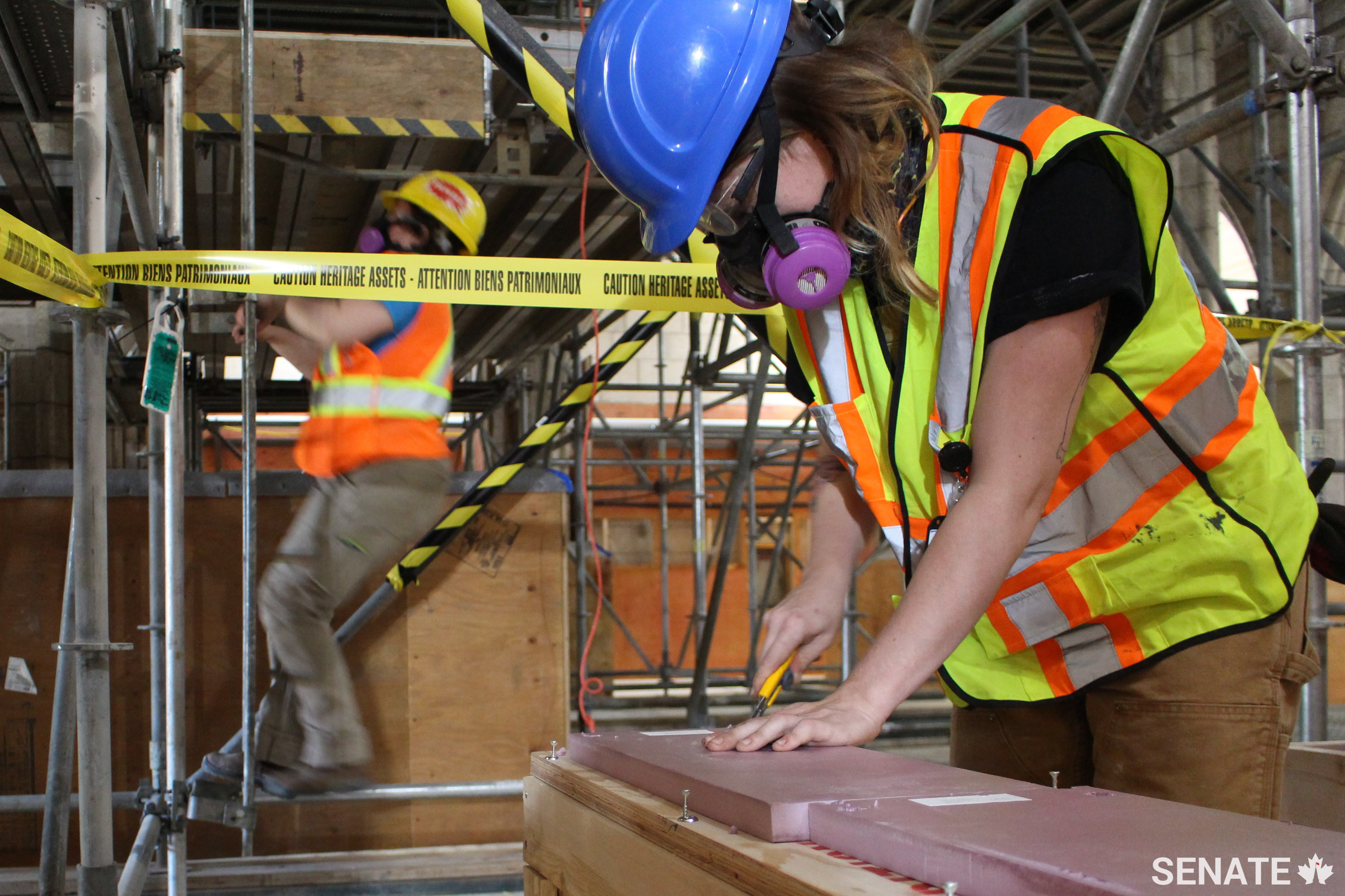 A worker trims supports to accommodate parts of the window. The window was removed in sections and fitted into wooden boxes.