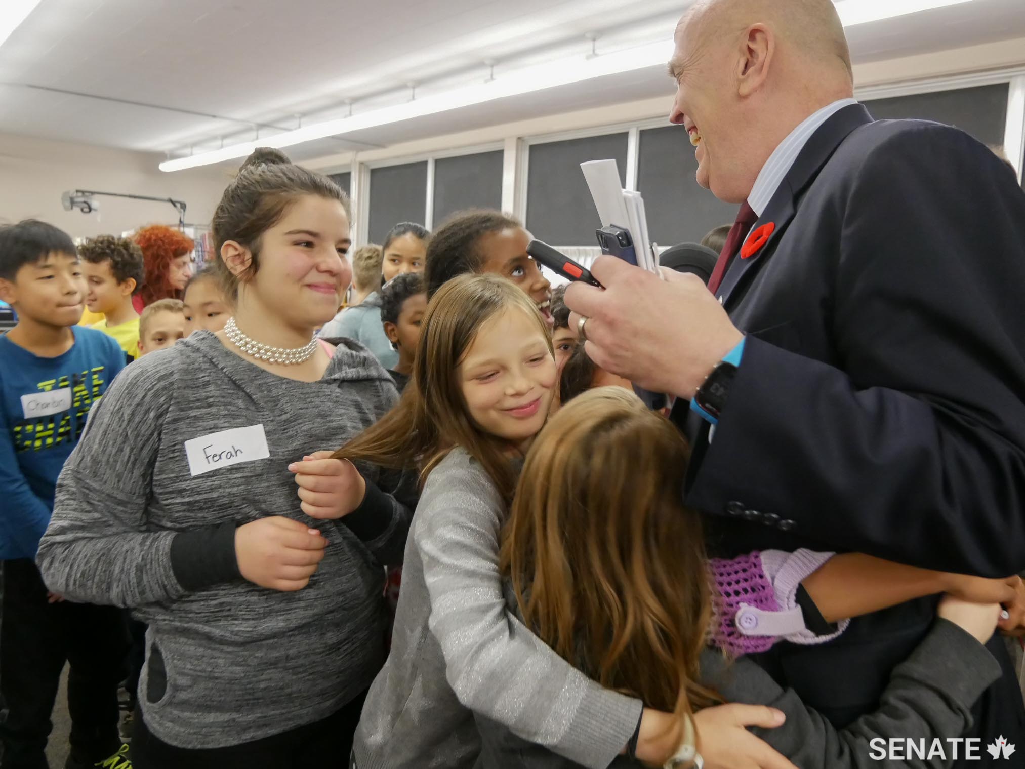Senator White gets hugs from Grade 4, 5 and 6 students at Arch Street Public School in Ottawa on November 2, 2017. The senator visited the school to speak about his role as a senator and about his previous career as a police officer.