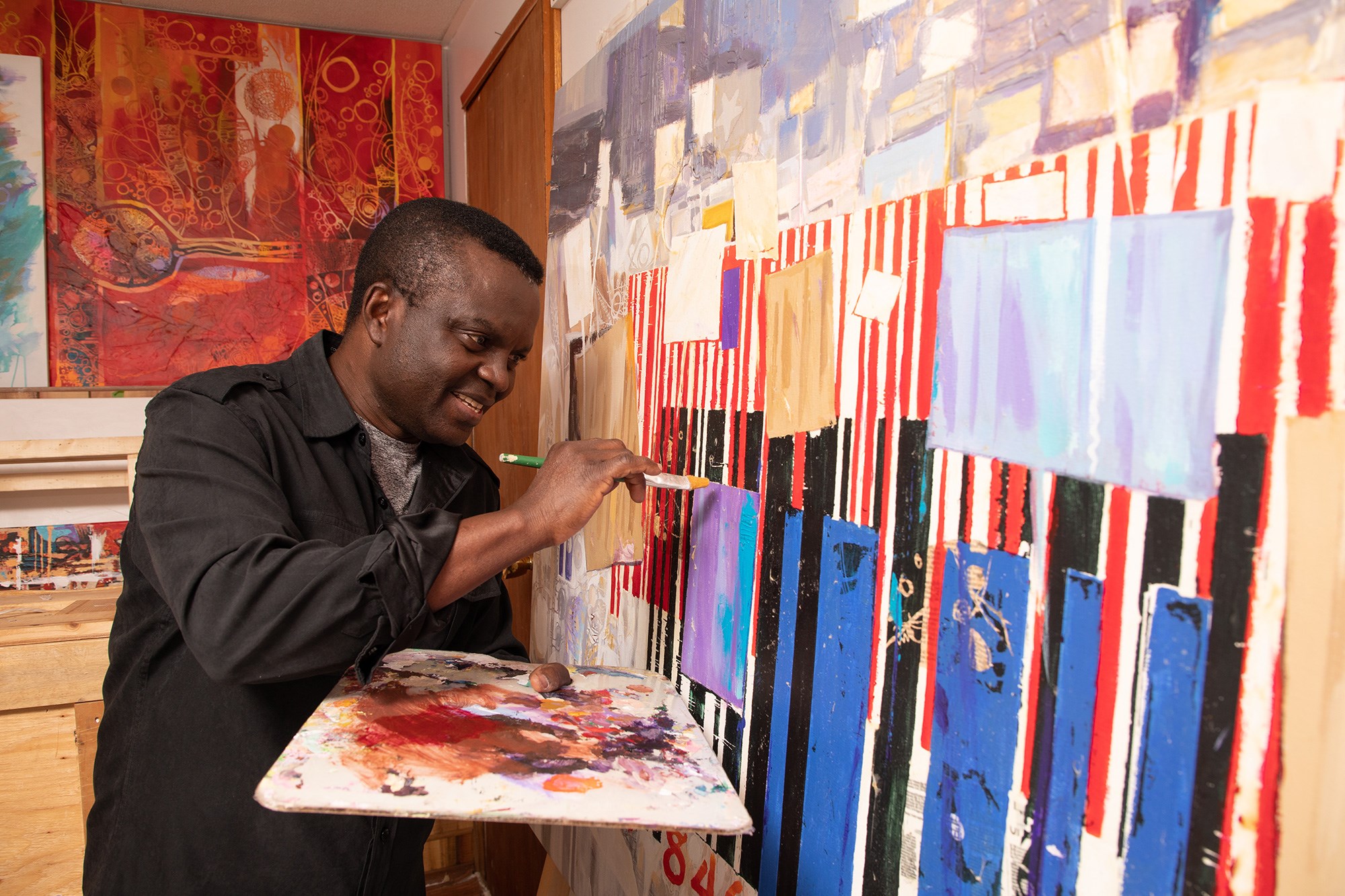 Yisa Akinbolaji paints in his Winnipeg, Man. studio on Thursday, September 17, 2020. The painting pictured here, inspired by the Black Lives Matter movement, is a work in progress. (Photo credit: Leif Norman)