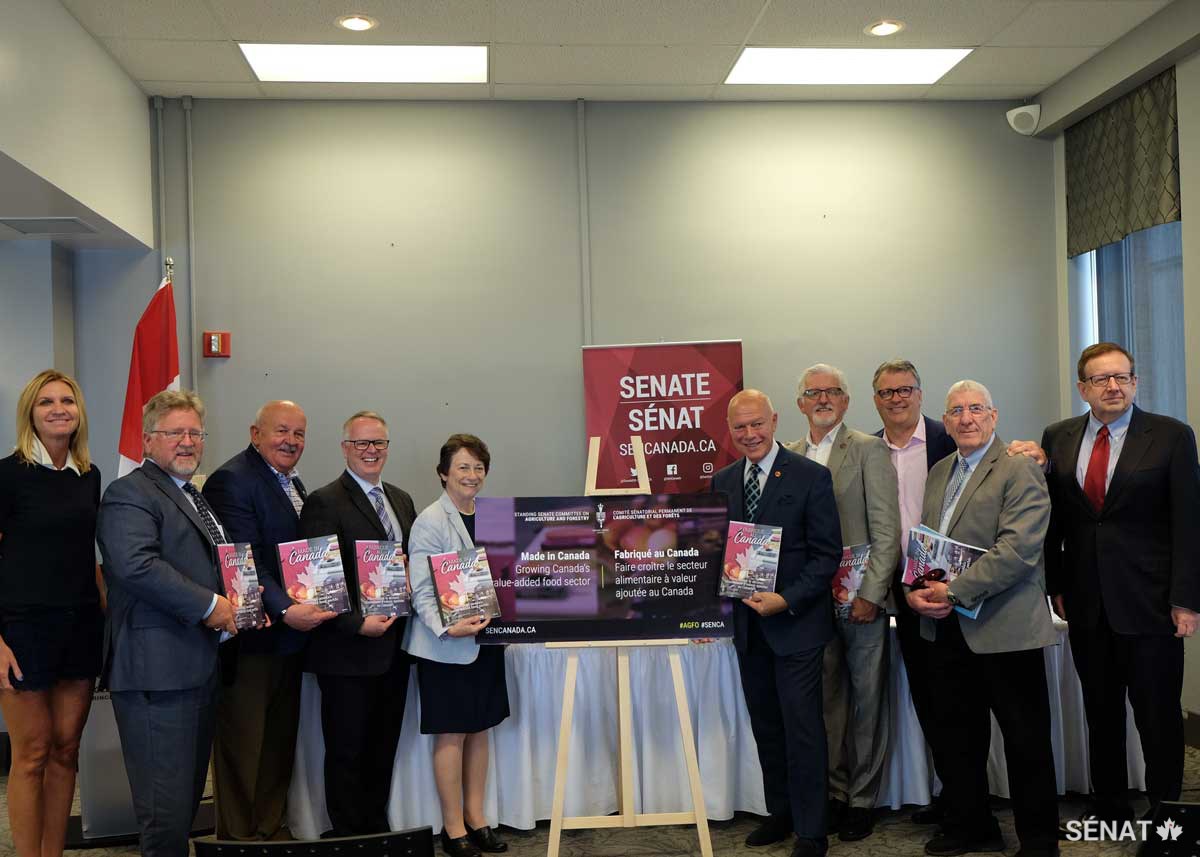 Le sénateur Doyle, deuxième à partir de la droite, participe au lancement du rapport du Comité sénatorial de l’agriculture et des forêts, <em>Fabriqué au Canada : Faire croître le secteur alimentaire à valeur ajoutée au Canada</em>, en 2019, avec des collègues du comité à Charlottetown, à l’Île du Prince Édouard.