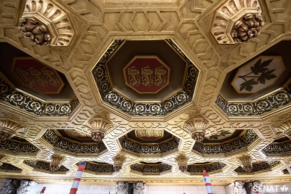 C’est bel et bien de l’or qui orne le plafond du Sénat. Des artisans ont réalisé ce processus laborieux en brossant de petits rectangles de minces feuilles d’or sur pratiquement toutes les surfaces de ce plafond en plâtre finement sculpté. Les motifs foncés sur la bande à l’intérieur des caissons ont été peints au pochoir.