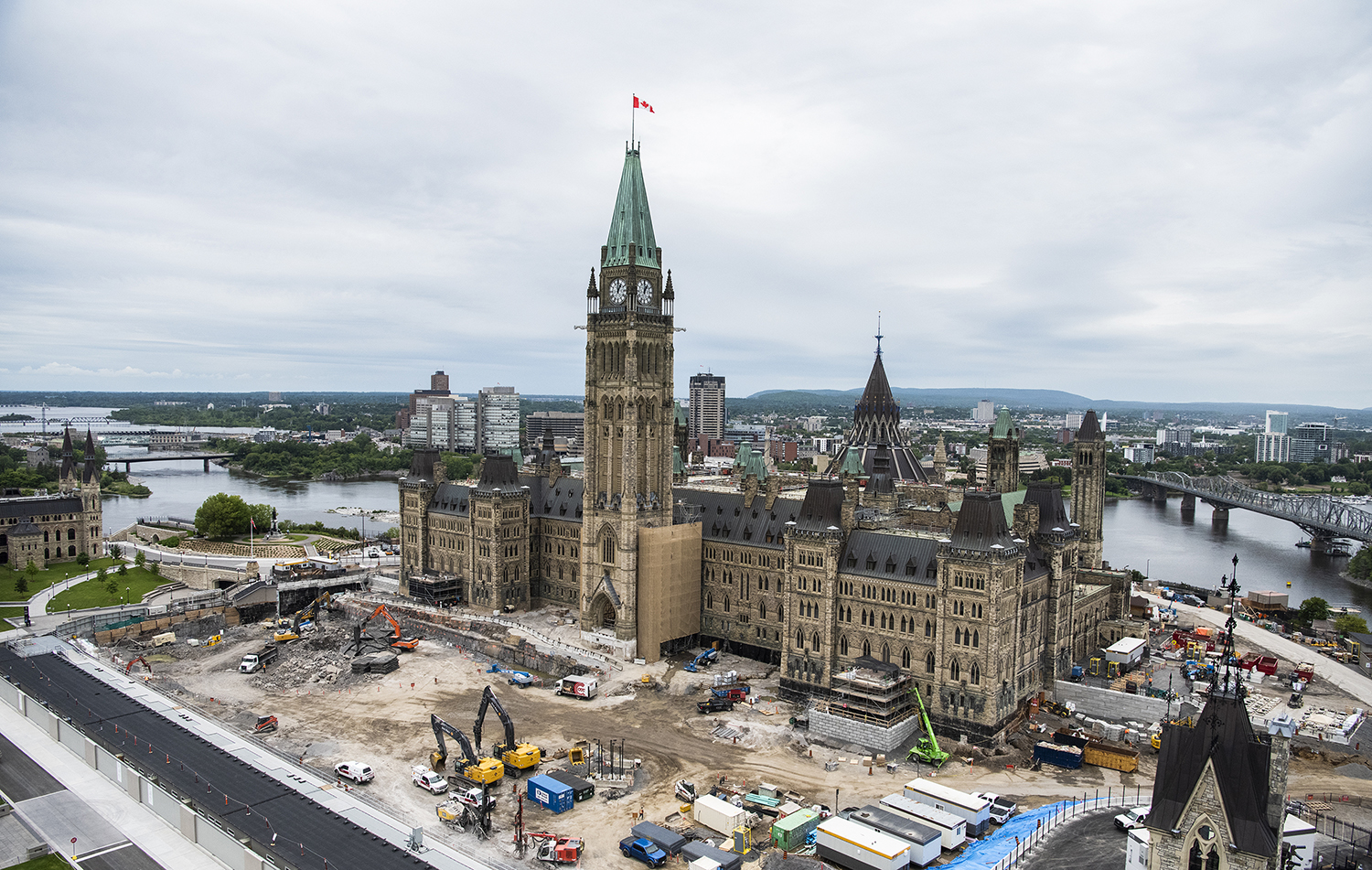 Cette vue du chantier de construction sur la Colline du Parlement montre les travaux d’excavation effectués sur le parterre sud, où sera construit un plus grand Centre d’accueil des visiteurs. Du côté droit, à l’extrémité est de l’édifice, on procède au déblaiement des fondations et au démontage du porche du Sénat, en vue des améliorations sismiques qui seront apportées à l’édifice. (Crédit photo : Services publics et Approvisionnement Canada)