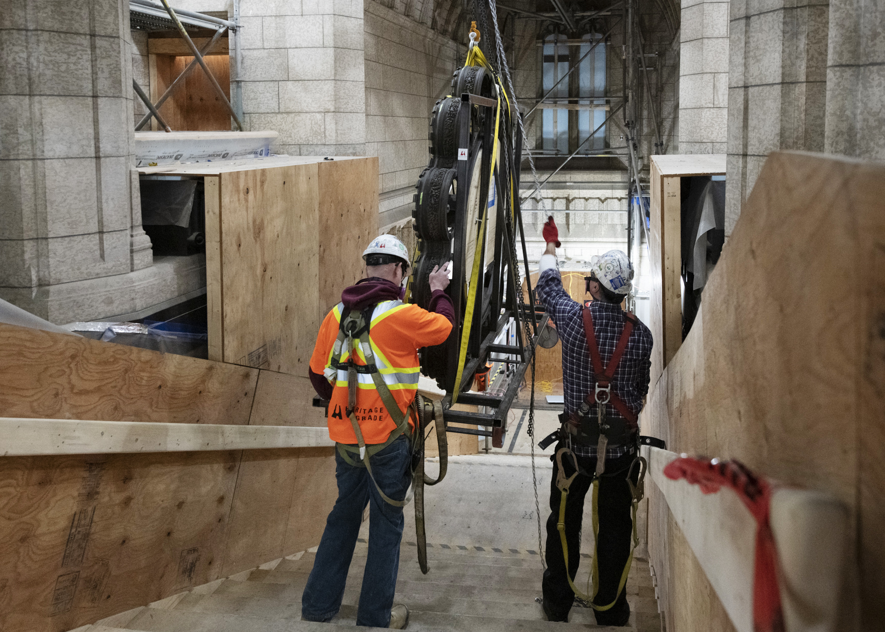 Workers navigate the next challenge: getting the ring and the frame down the stairs of the Senate foyer and out of the building. The crew devised another custom pulley system for that purpose, which includes an overhead track so the frame can glide over and down the staircase. (Photo credit: Public Services and Procurement Canada)