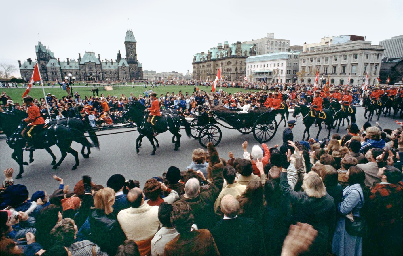 Queen Elizabeth and Prince Philip wave to crowds on Parliament Hill as they ride in an open carriage, escorted by RCMP officers, during the Queen’s Silver Jubilee visit to Canada in 1977. The Queen later opened Parliament with the reading of the Speech from the Throne from the Senate Chamber. (Photo credit: The Canadian Press)