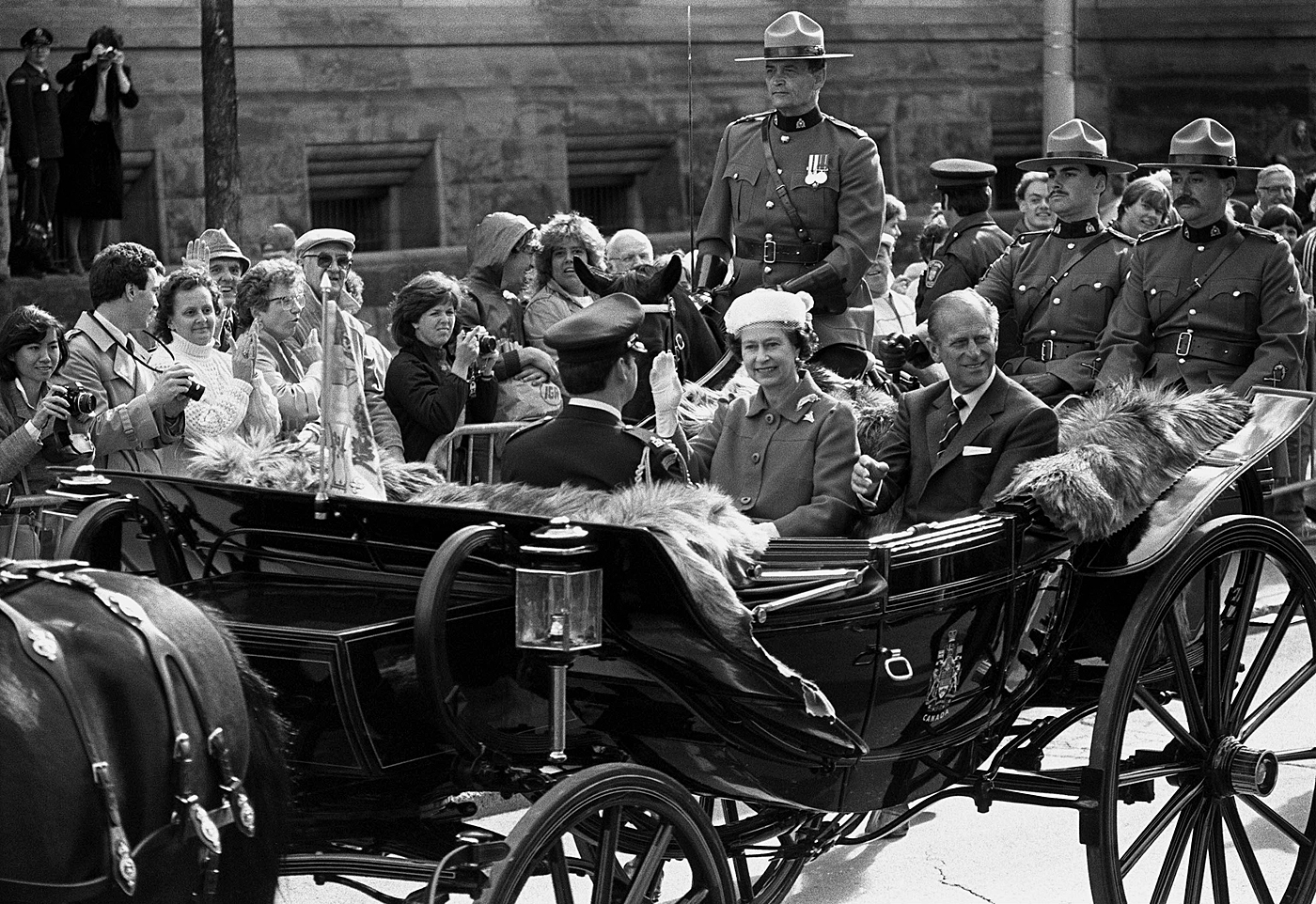 During their 16th visit to Canada in September 1984, Queen Elizabeth and the Duke of Edinburgh wave to crowds of supporters as they depart Parliament Hill for Rideau Hall, the official residence of the governor general. (Photo credit: The Canadian Press)