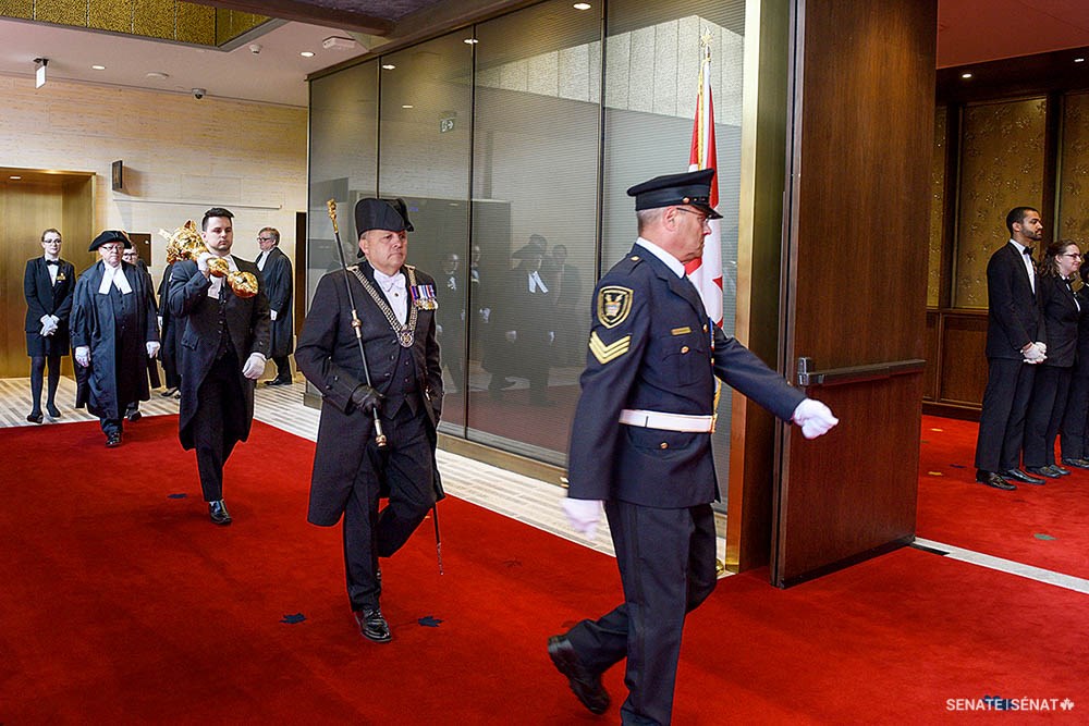 La masse en action : Pendant le défilé du Président, l’huissier du bâton noir et le porteur de la masse précèdent le Président dans l’édifice du Sénat du Canada en direction de la Chambre du Sénat.