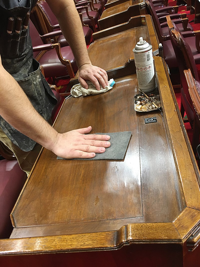 Mr. Mailhot polishes a protective wax finish into the surface of each desk. (Photo credit: Ottawa Furniture Repair)