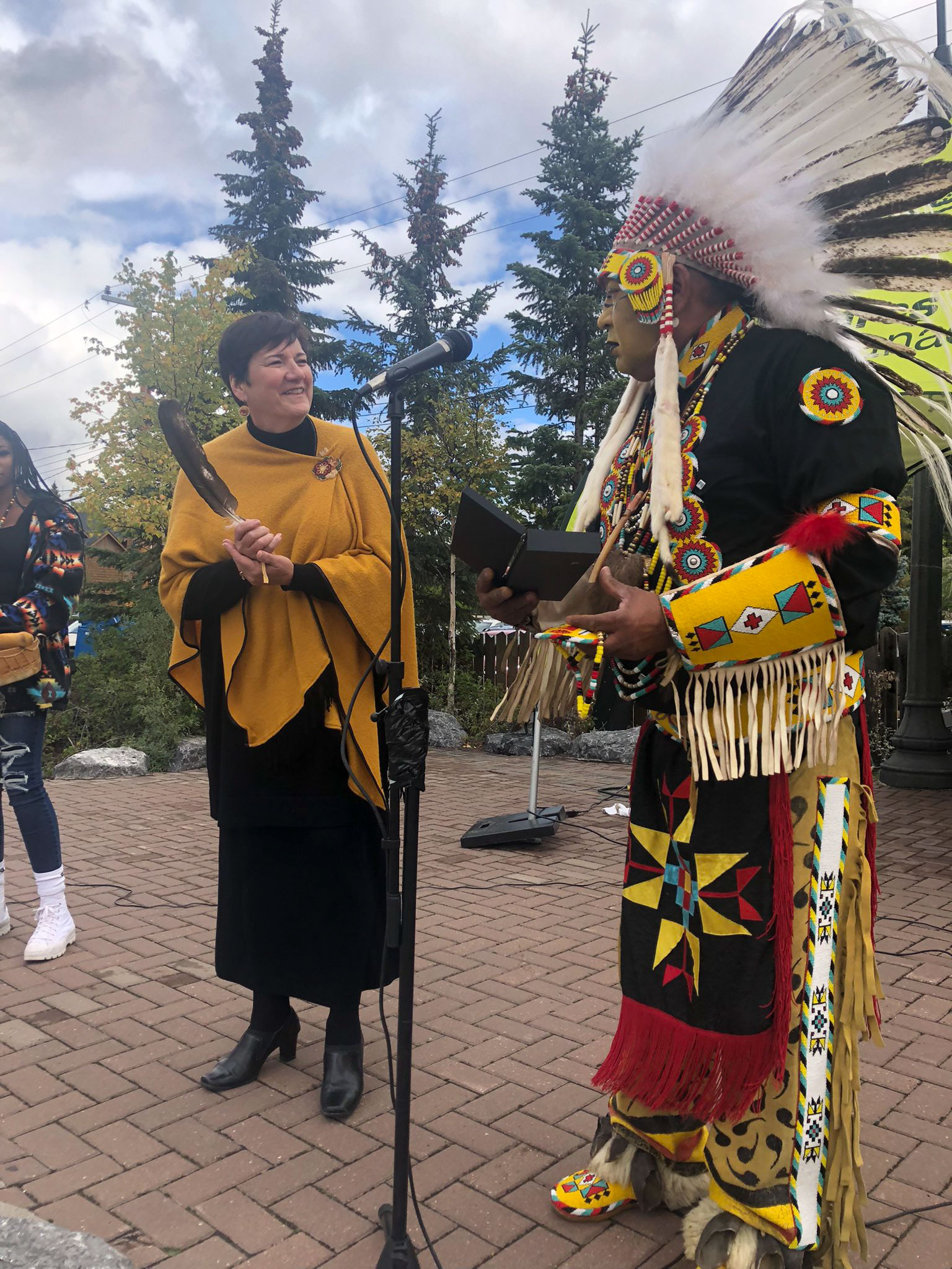 Saturday, September 18, 2021 – Senator Karen Sorensen humbly accepts an eagle feather, a great honour, from Elder Treffrey Deerfoot. The senator will take the eagle feather with her to Ottawa and place it prominently in her office, where it will be used for guidance as she prepares for discussion and debate in the Senate. Elder Deerfoot and his group, Blackfoot Medicine Speaks, often perform in Banff, Alberta.  It’s an opportunity for dance, entertainment, and reflection as Elder Deerfoot takes the time to educate the audience throughout his performance with stories of Blackfoot culture.