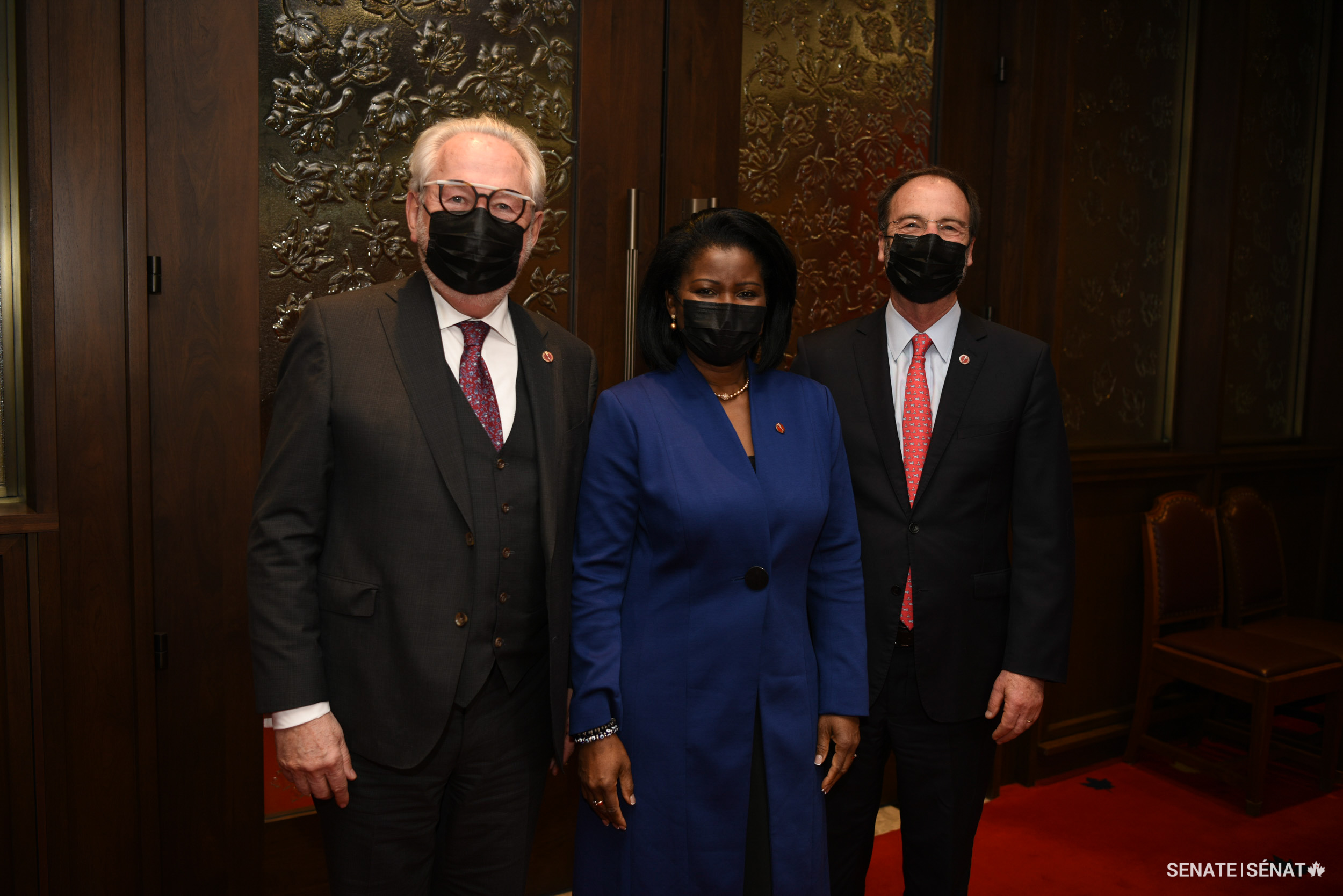Senator Amina Gerba, centre, stands with senators Peter Harder and Marc Gold after her swearing-in ceremony.