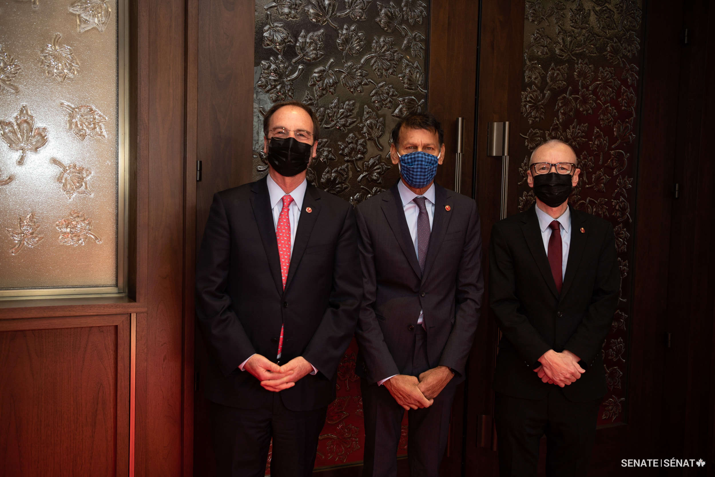 Senator Hassan Yussuff, centre, stands with senators Marc Gold and Tony Dean after his swearing-in ceremony.