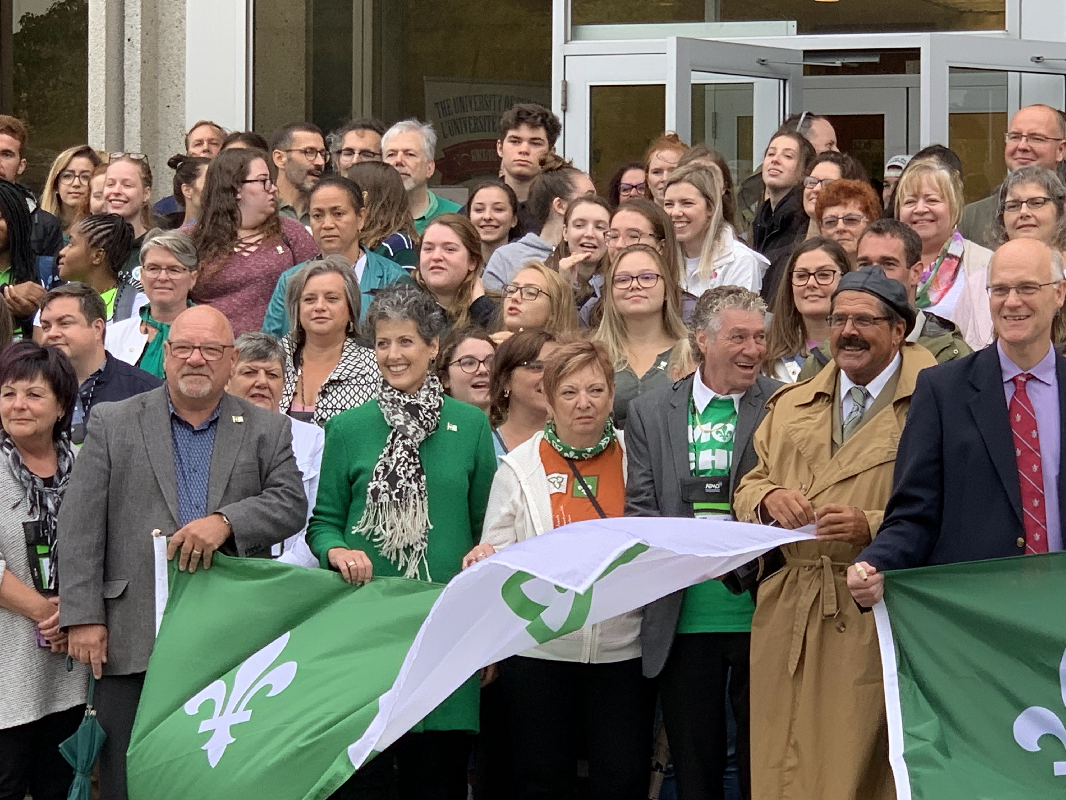 Senator Forest-Niesing helps hold the Franco-Ontarian flag on September 25, 2019 at the University of Sudbury, where the flag was officially raised for the first time in 1975.