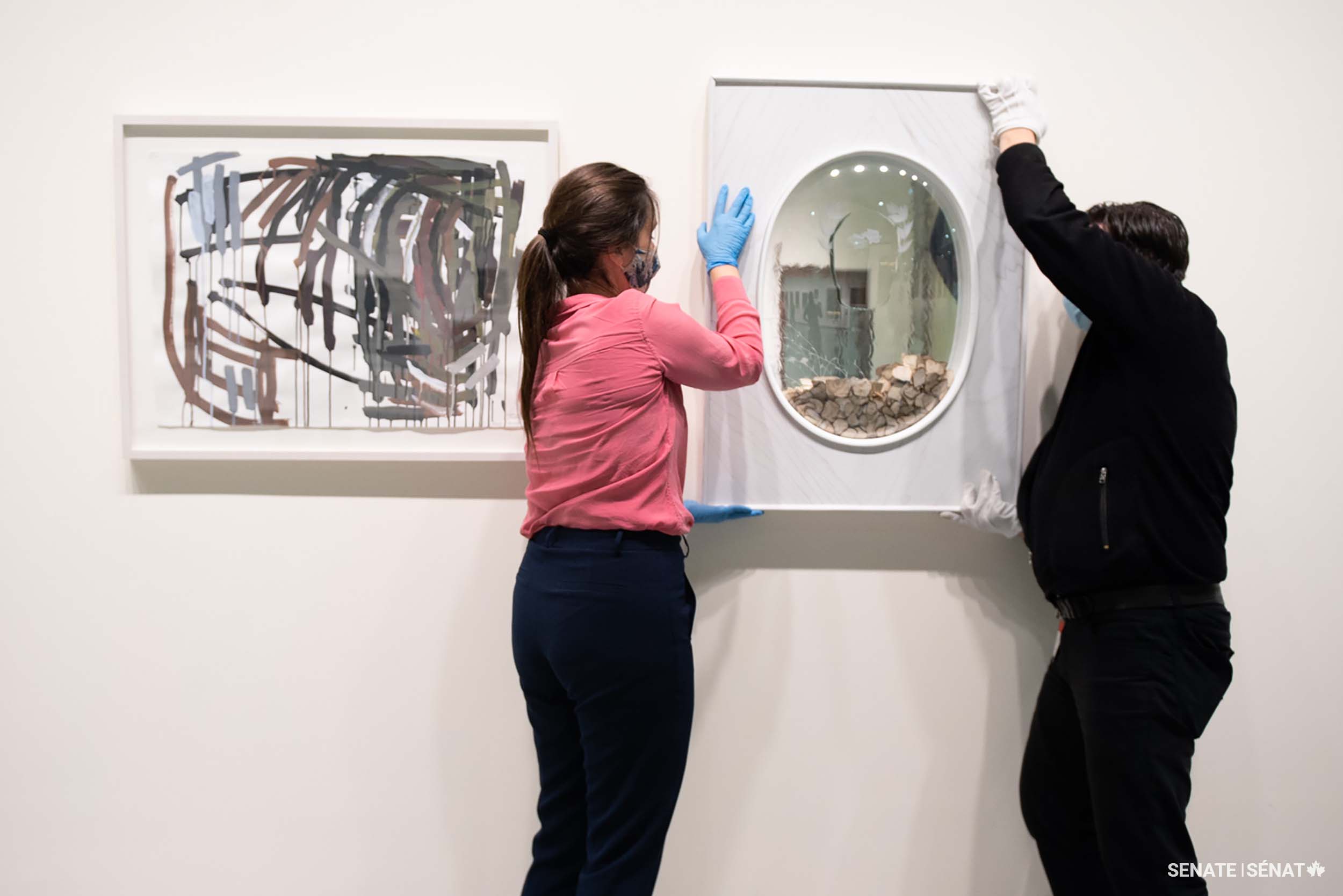 Ms. Dolan helps place Light Laureate on the wall beside Ms. Thomasos’ painting.