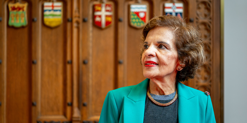 Senator Mobina S.B. Jaffer stands in front of the original Senate antechamber doors featuring provincial and territorial shields.