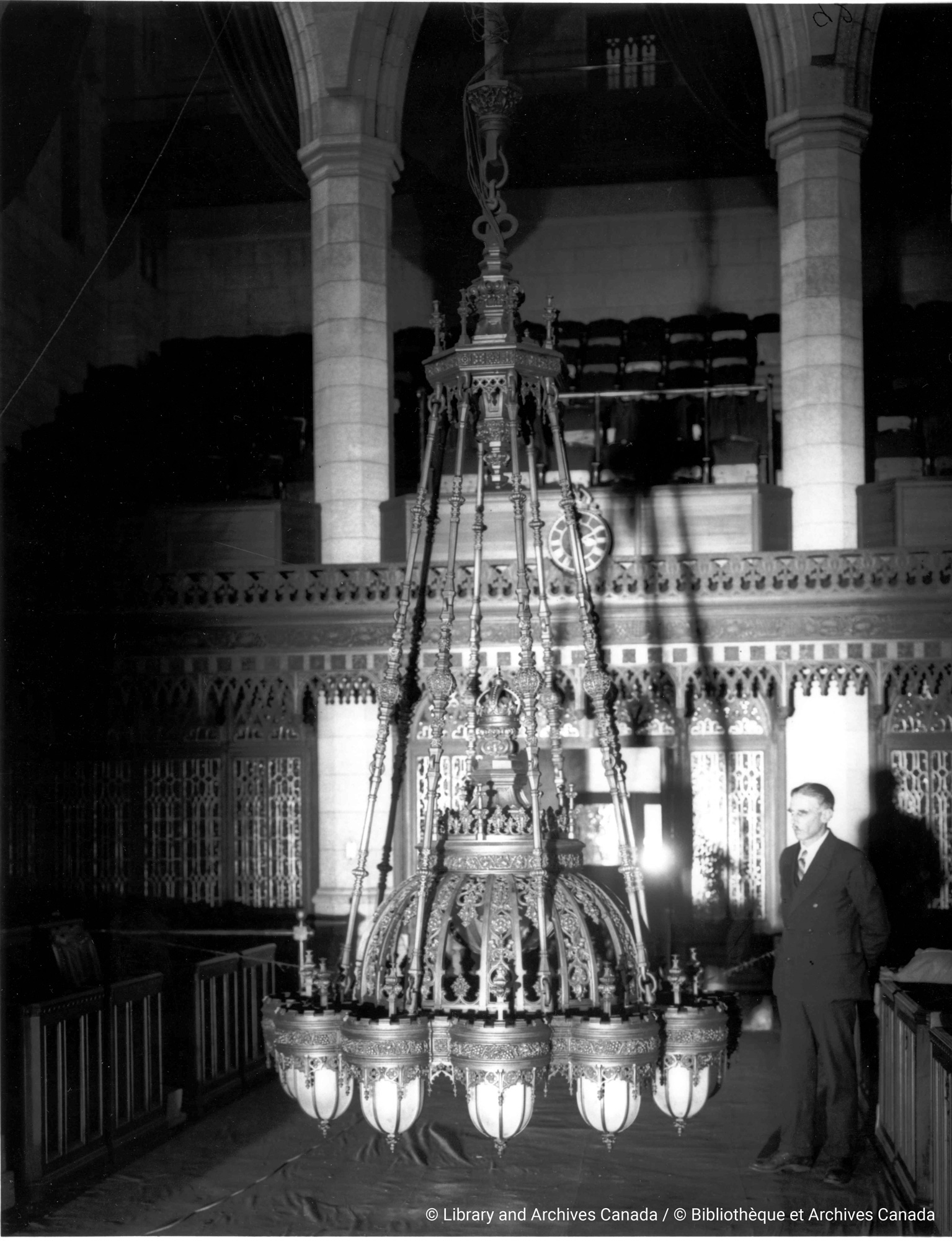 This undated photograph shows one of the Senate chandeliers, with its original egg-shaped lanterns, suspended close to the floor of the Red Chamber. (Photo credit: Library and Archives Canada)