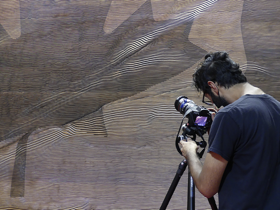Abhijit Dhanda, chef d’équipe du CIMS, photographie l’un des panneaux en noyer gravé d’un drapeau canadien qui flotte au vent.