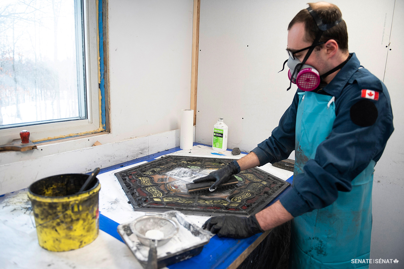 Each window is finished with a coating made of calcium carbonate, linseed oil and black pigment. Conservator Hayden Maynard works the thick putty into every joint, then scrubs the excess off with a hog-hair brush.