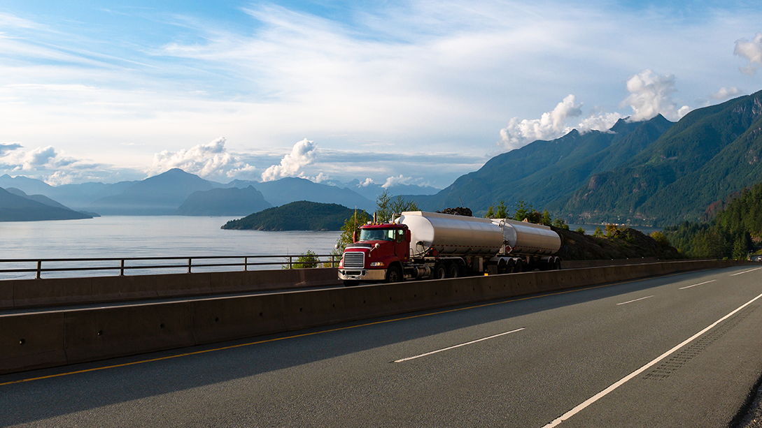 A fuel tanker driving along a coastal highway.