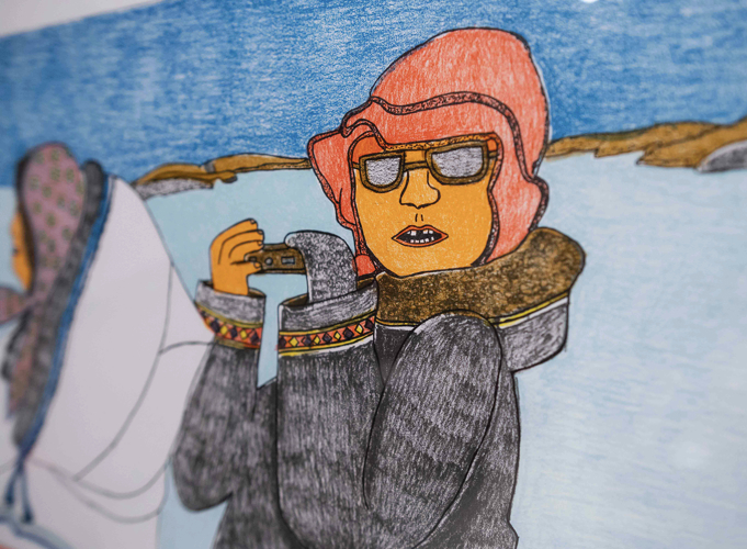 A coloured print depicting a woman holding a camera and wearing a hat, parka and sunglasses, with a northern landscape in the background.