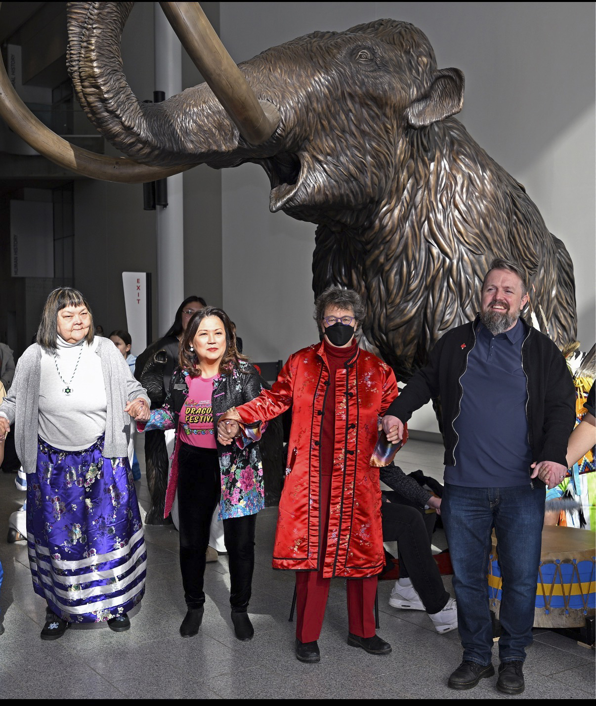 Un groupe de personnes se tenant devant une statue de mammouth