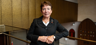 A woman leans against a railing in the Senate of Canada Building.