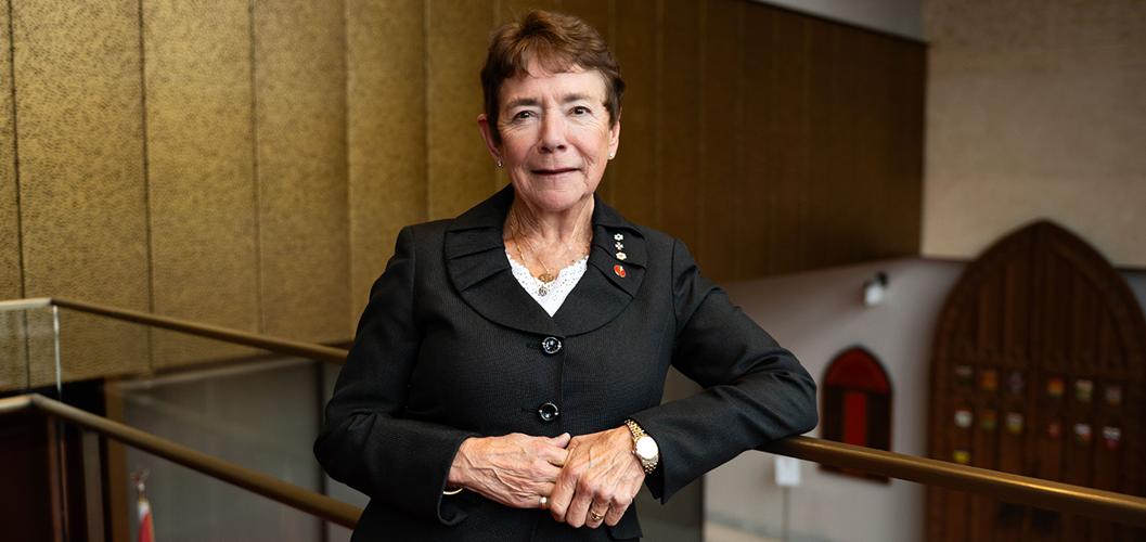 A woman leans against a railing in the Senate of Canada Building.