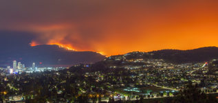 A wildfire burns on a mountainside near a town.