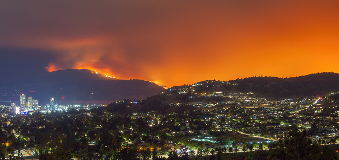 A wildfire burns on a mountainside near a town.