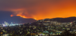 A wildfire burns on a mountainside near a town.
