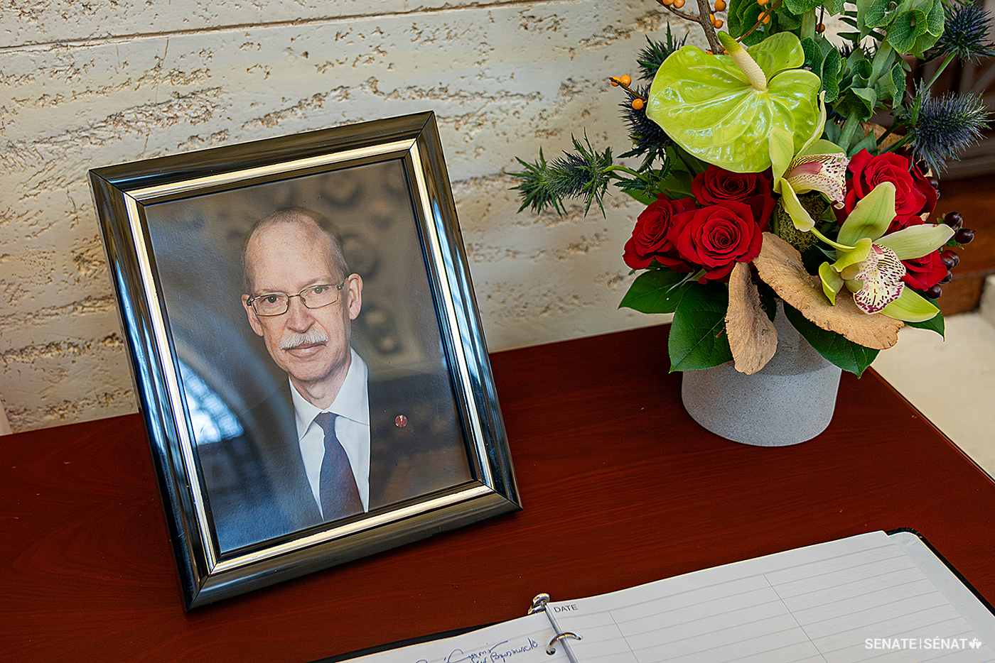 A photo of Senator Shugart sits on a table in the Senate of Canada Building, where friends, colleagues and visitors signed a book of condolences.