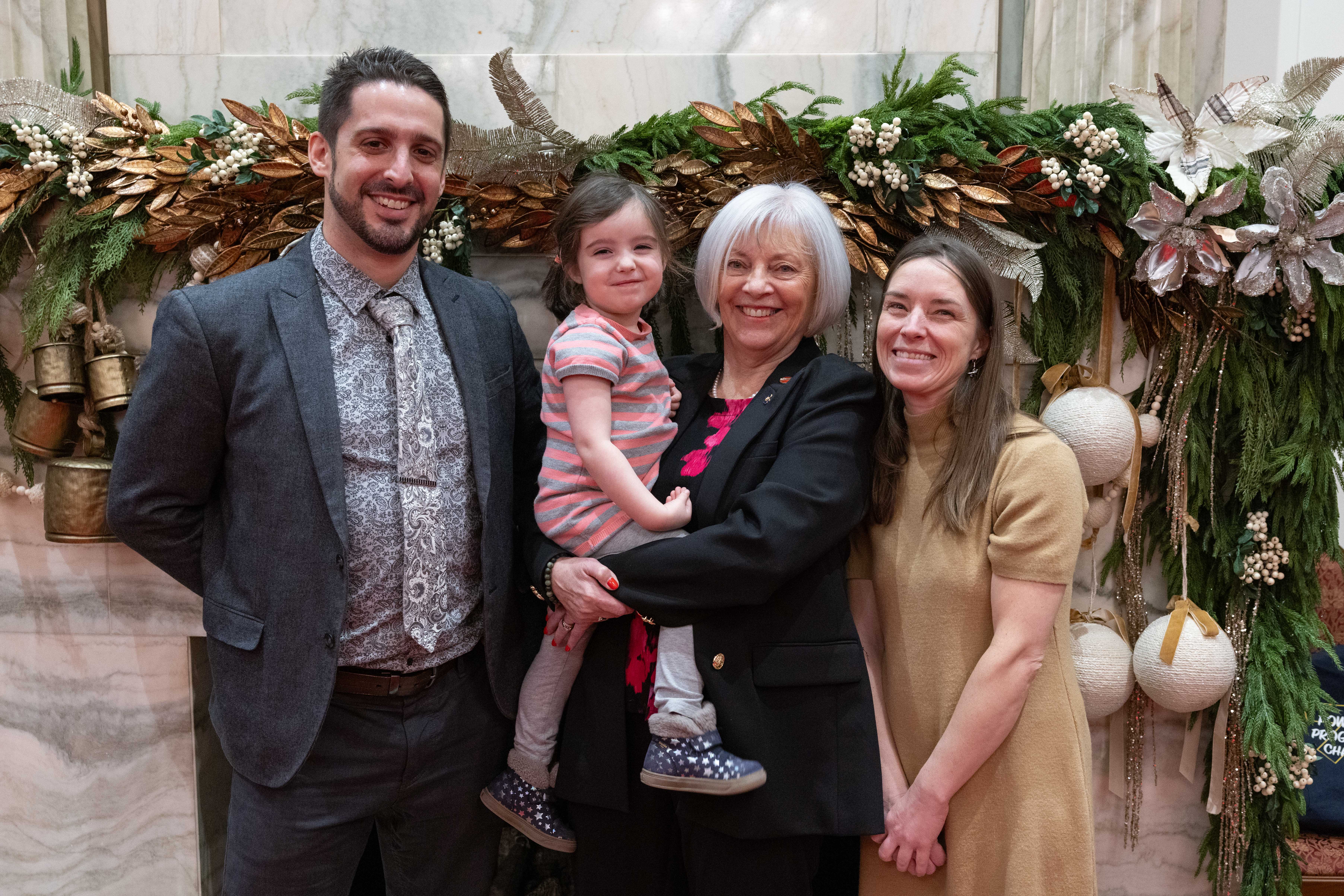 Senator Hartling holds Freyja, daughter of Anthony Lamoureux — who was the senator’s director of parliamentary affairs — and Alissa. (Photo credit: Office of Senator Nancy J. Hartling)