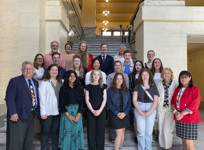 Senators Rob Black and Judy A. White stand with a group of students in the staircase of the foyer in the Senate of Canada Building.