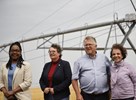 Les sénateurs Sharon Burey, Paula Simons, Rob Black et Mobina Jaffer devant un arroseur géant, dans un champ de blé de l’entreprise Auch Farms, près de Carmangay (Alberta).