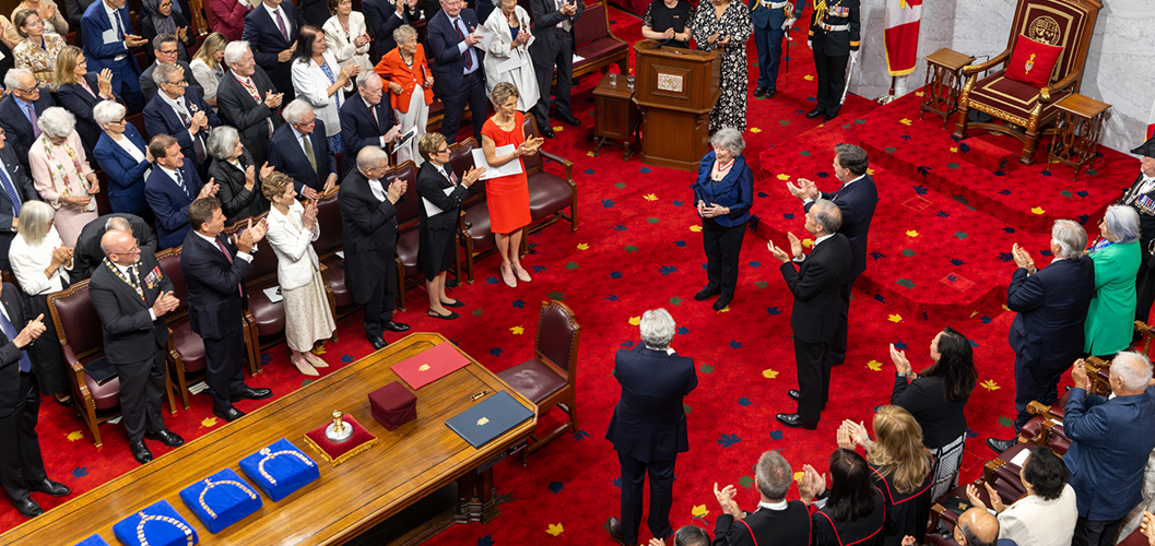 Une femme debout devant un trône est applaudie par une foule dans la Chambre du Sénat.