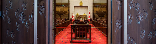 Vue de la Chambre du Sénat dans l’édifice du Sénat du Canada à travers les portes ouvertes.