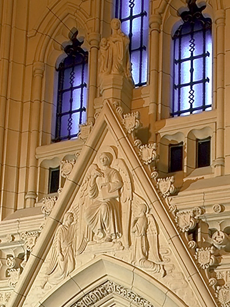 Dans le tympan au-dessus de l’entrée de la Chapelle du Souvenir, l’ange enregistreur, flanqué d’anges assistants, écrit le nom des morts dans le Livre du Souvenir. (Crédit photo : Bibliothèque du Parlement)