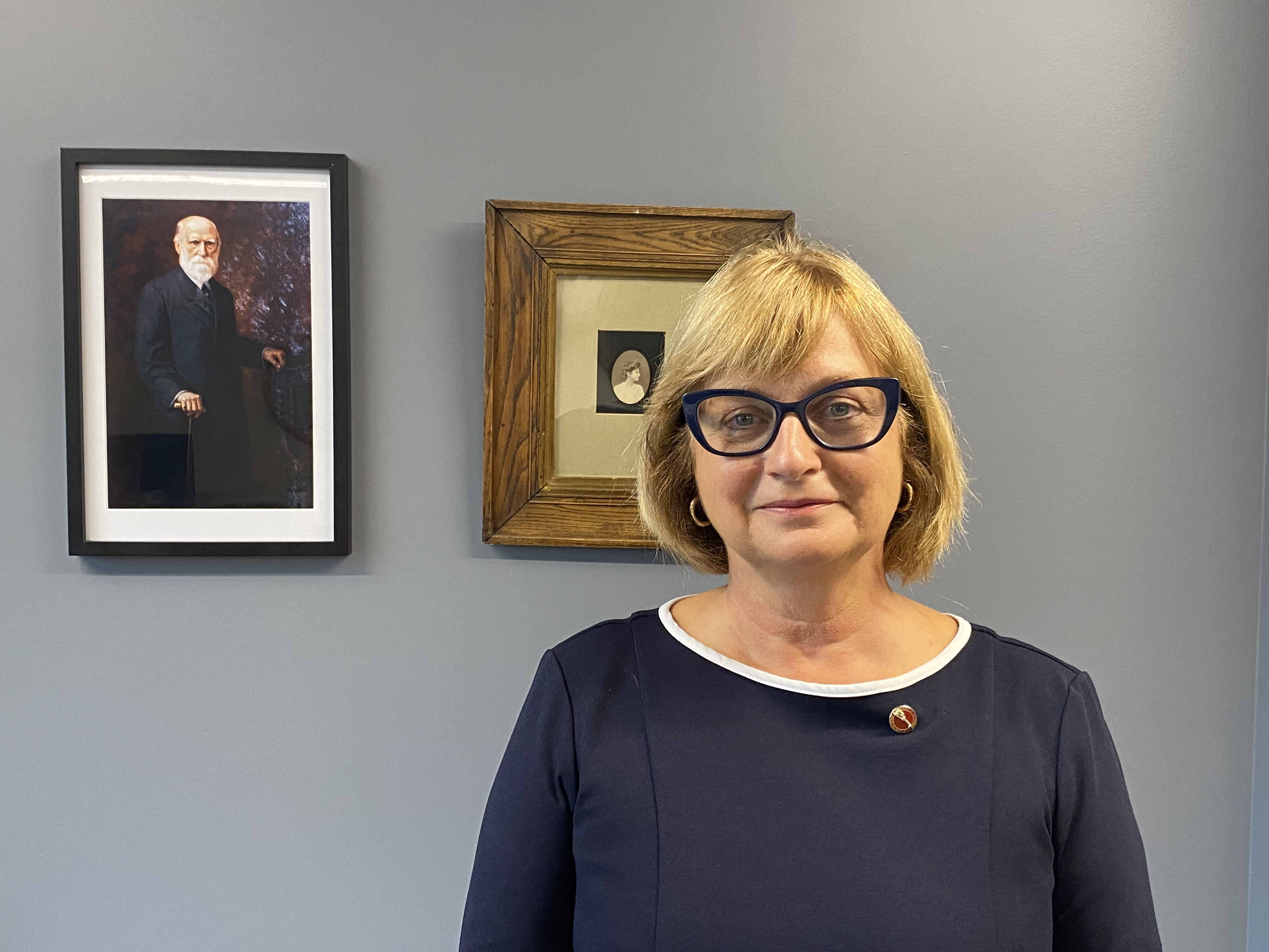 La sénatrice Julie Miville-Dechêne devant un portrait de son arrière-arrière-grand-père, le sénateur Georges-Casimir Dessaulles, et de son arrière-grand-mère, la journaliste Henriette Dessaulles : un sénateur centenaire, une pionnière du journalisme féminin et une journaliste devenue sénatrice. (Crédit photo : Bureau de la sénatrice Julie Miville-Dechêne)