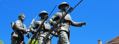 A statue of three marching soldiers armed with rifles and bayonets in front of Province House in Charlottetown, Prince Edward Island.