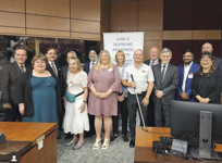 Group photo of members of the deafblind community with senators Percy Mockler, Tony Loffreda, Brent Cotter, Elizabeth Marshall, Sabi Marwah, Yonah Martin, and former senator Vim Kochhar, in a committee room.