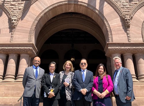 From left, senators Andrew Cardozo, Kim Pate, Donna Dasko, Victor Oh, Salma Ataullahjan, and Rob Black, standing in front of the Ontario Legislature.