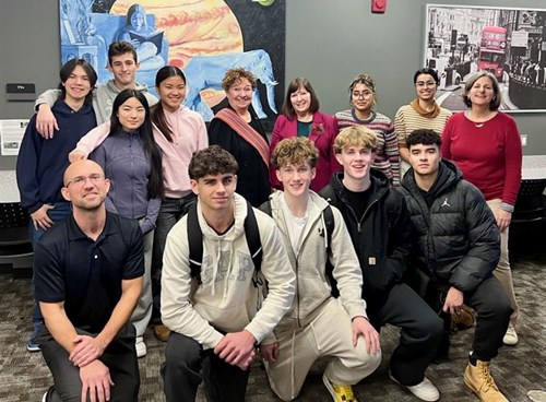 A group of students, teachers, and senators pose for a photo during a visit to a high school.