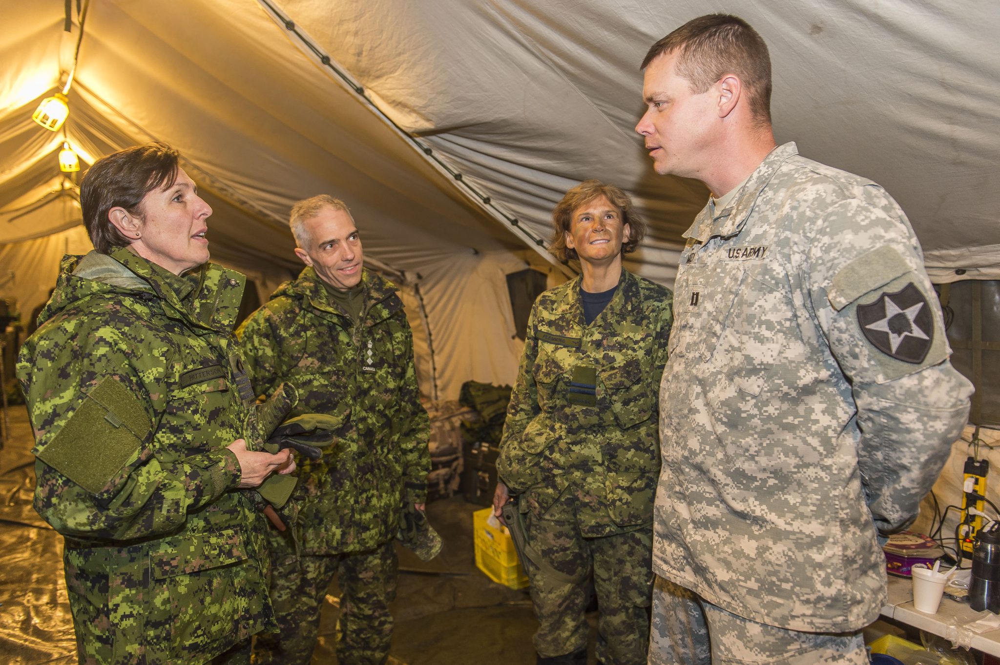 La capitaine de vaisseau Patterson s’entretient avec l’aumônier de l’armée américaine le capitaine Chris McCarley, à droite, le colonel Marc Bilodeau et la capitaine Deborah Flemming à l’unité de soutien médical de rôle 1 supérieur à Wainwright, en Alberta, en 2016. (Crédit photo : Caporal-chef Jonathan Barrette; image : caméra de combat des FC)