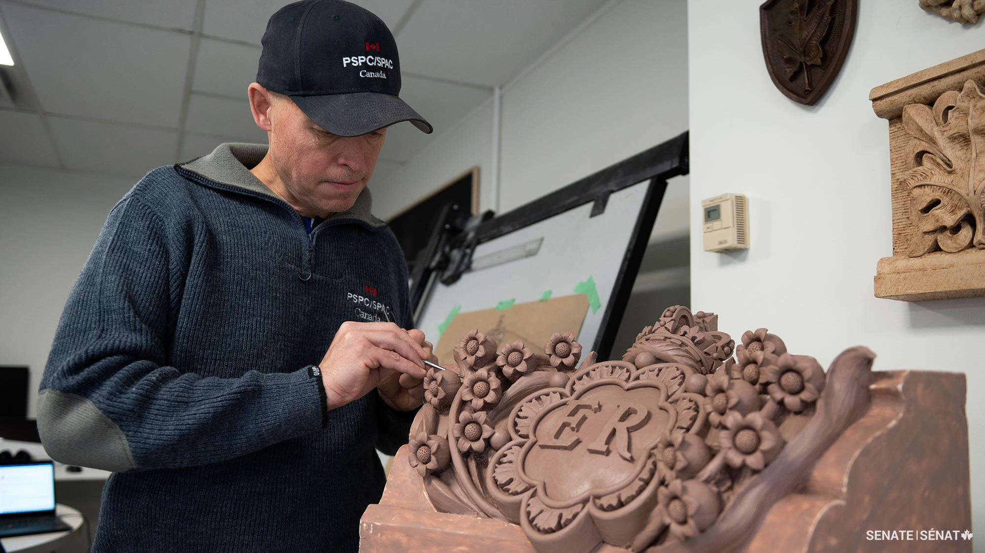 Mr. Smith applies finishing touches to one of the decorative lilies on the clay model.