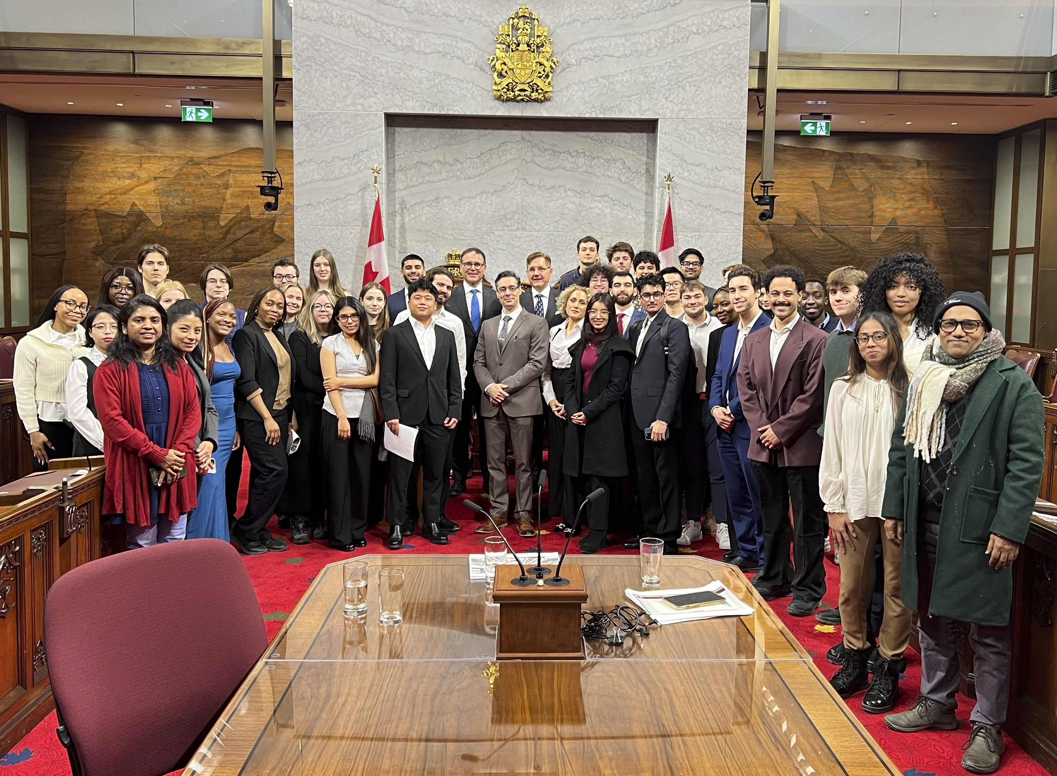 Un groupe d’étudiants et de sénateurs posent pour une photo dans la Chambre du Sénat. 