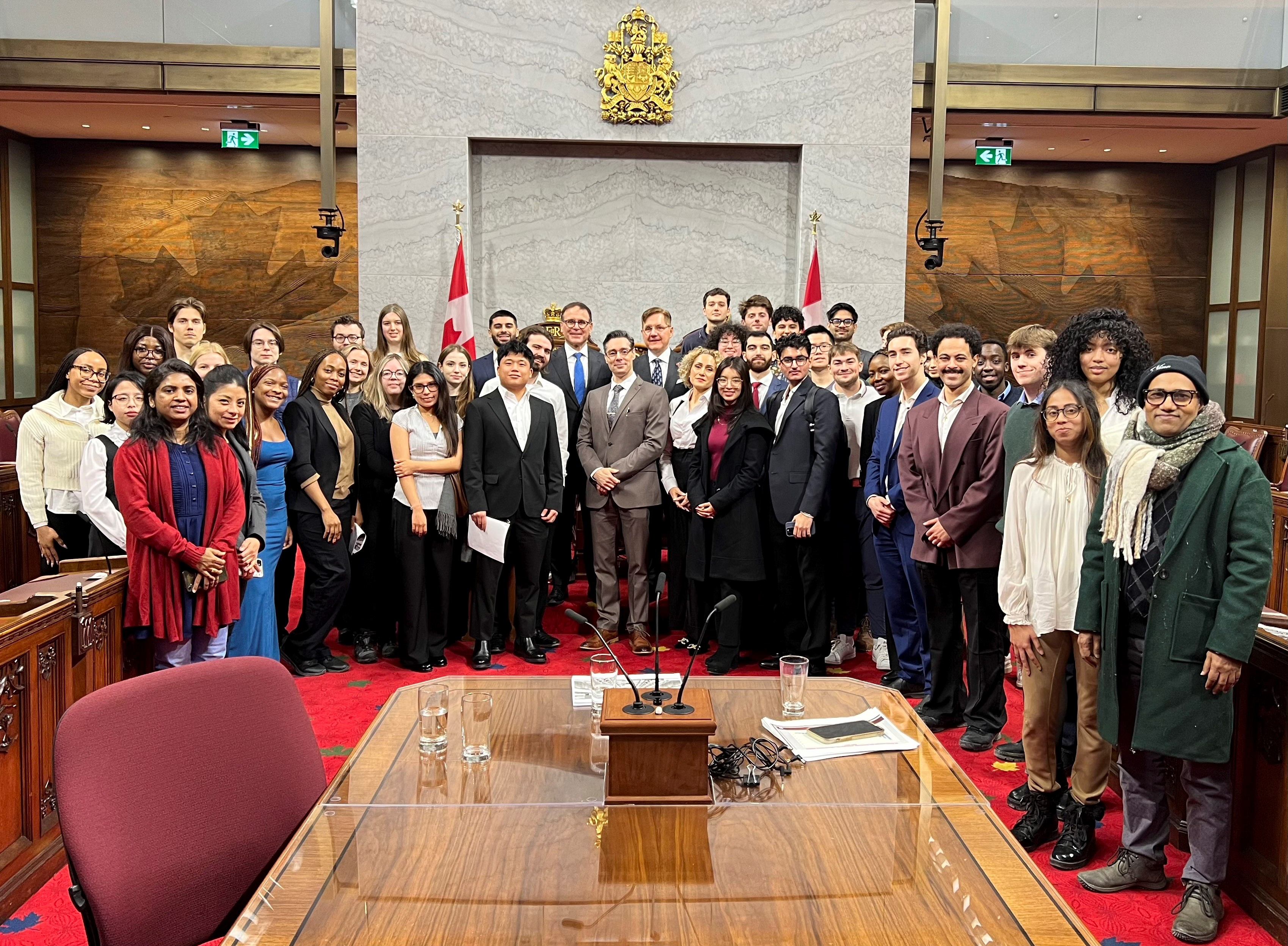 Un groupe d’étudiants et de sénateurs posent pour une photo dans la Chambre du Sénat. 