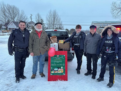 Senator Percy Mockler with RCMP officers and a community member standing by a pickup truck filled with boxes of food.