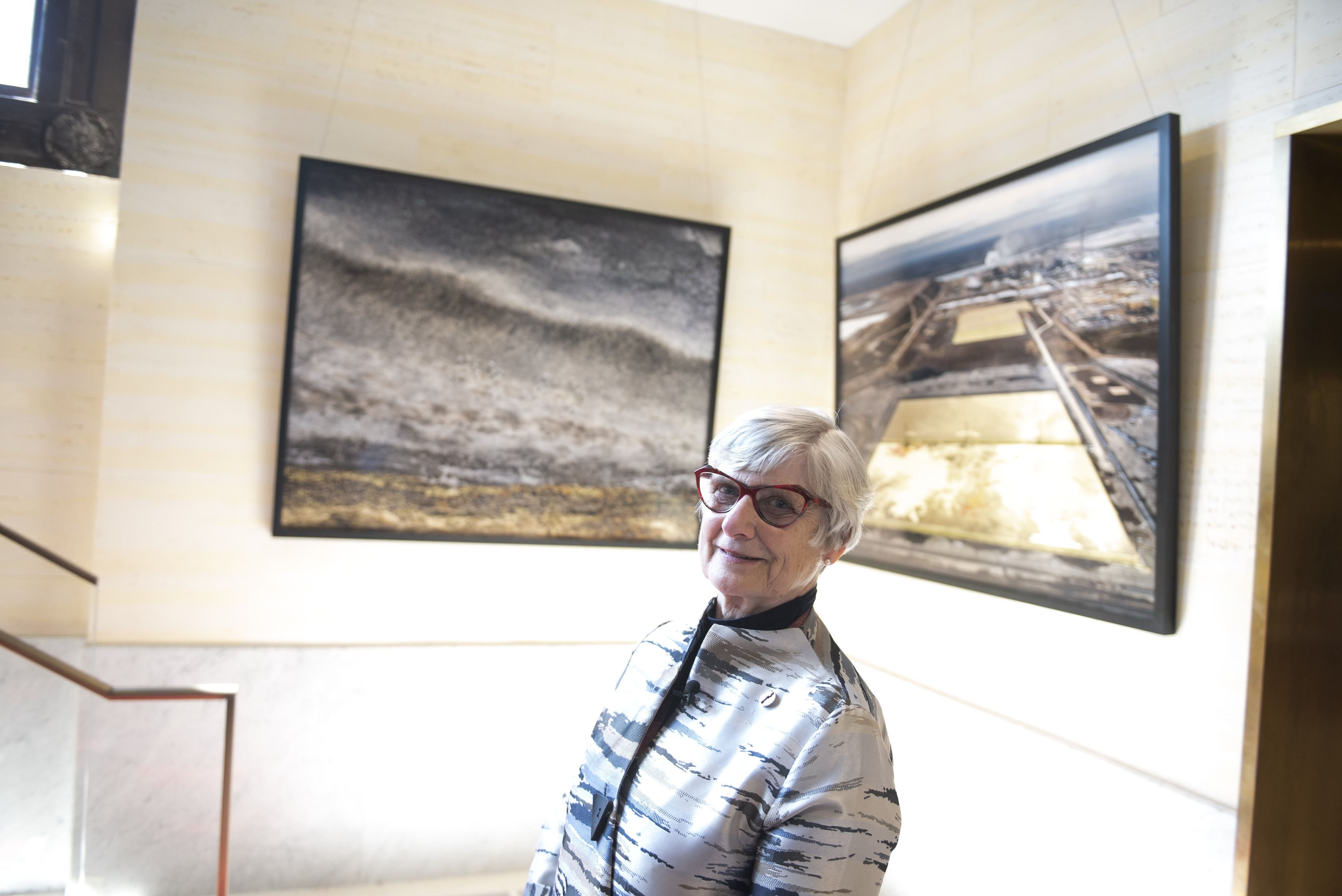 Senator Bovey stands in front of “Visual Voices: Artists & the Environment,” which will be on display in the Senate of Canada Building until the end of March 2023.