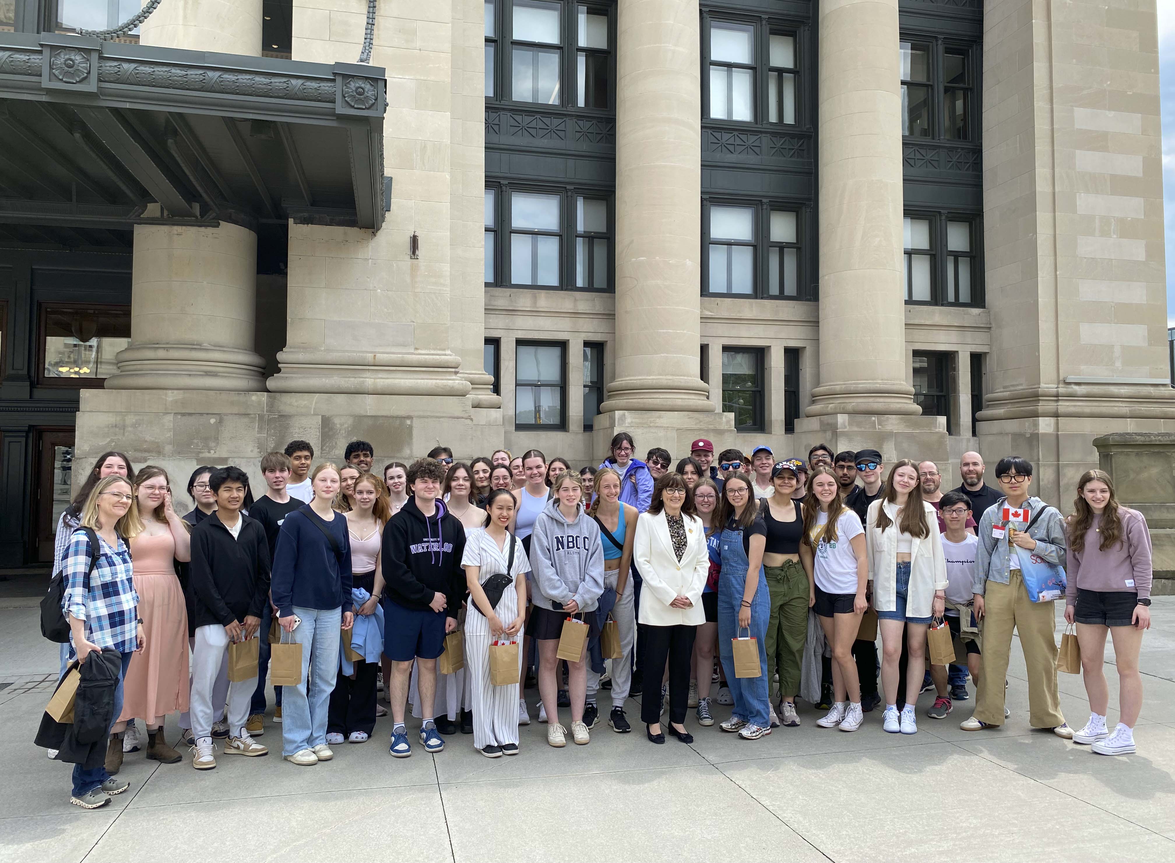 A group of people standing in front of the Senate of Canada Building entrance.