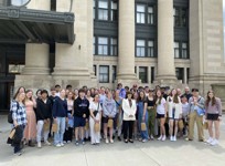 A group of people standing in front of the Senate of Canada Building entrance.