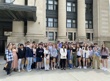 A group of people standing in front of the Senate of Canada Building entrance.
